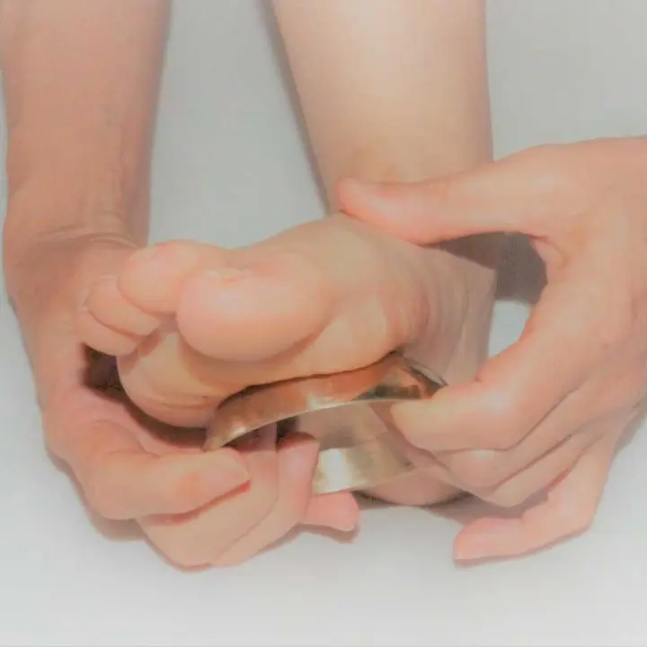 Massage des pieds avec bol kansu – technique ayurvédique de réflexologie plantaire.
